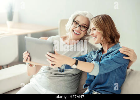 Gioiosa donna sorridente e sua figlia adulta in appoggio a casa Foto Stock