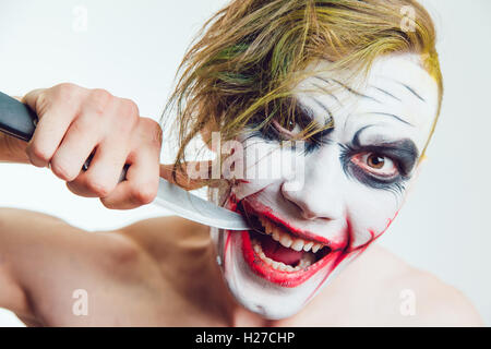 L'uomo con la faccia di Halloween arte con un coltello in mano su sfondo bianco Foto Stock