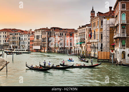 3 gondola nel mezzo del Canal Grande di Venezia al tramonto contro il coloratissimo palazzi e case a fianco di questo trasporto principale Foto Stock