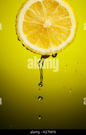 Splash succo con fettina di limone isolato su sfondo giallo Foto Stock