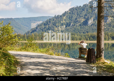 Un uomo su una panchina visualizzazione panorama sul lago di Offensee nel Salzkammergut Austria Foto Stock