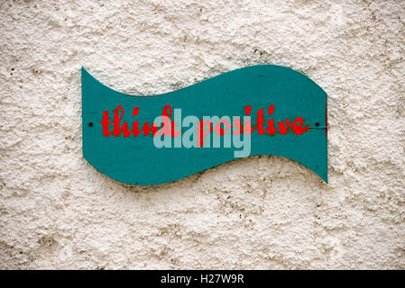 Pensare positivo segno scritta sul muro. Foto Stock