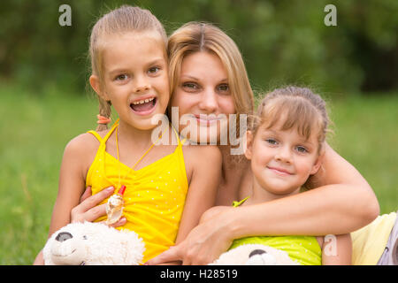 Giovane madre abbraccia le sue due figlie di 5 e 7 anni Foto Stock