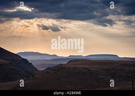 Cielo drammatico, nubi e raggi di sole incandescente su valli, canyon e tabella montagne del maestoso Golden Gate Highlands Foto Stock