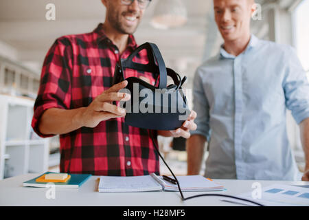 Colpo di due uomini utilizzando la realtà virtuale gli occhiali di protezione in Office. Business Partner di lavoro in ufficio, sta in piedi in una tabella con VR glasse Foto Stock