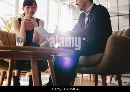 Due colleghi aziendale a discutere idee di business utilizzando digitale compressa. Giovane imprenditore avente incontro con partner di sesso femminile in Foto Stock