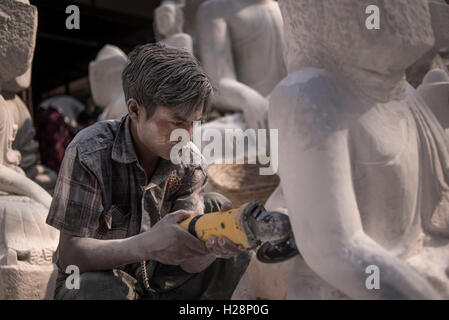 Un uomo locale scultura in marmo di una statua del Buddha usando una smerigliatrice angolare, Amarapura, vicino a Mandalay, Myanmar. Foto Stock