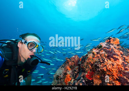 Giovane uomo scuba diver esplorare fondali. La vita subacquea con splendide rocce coralline e Foto Stock