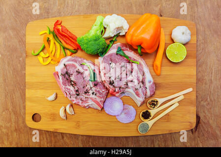 Carne cruda bistecche con spezie sul nero tagliere. Foto Stock