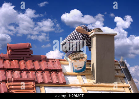 Copritetti builder lavoratore la riparazione di un camino sul tetto di una casa Foto Stock