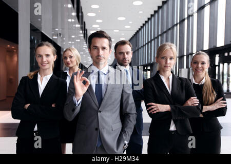 Ritratto di business di successo di uomo che mostra segno OK con il suo team Foto Stock