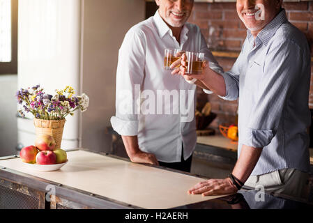 Due uomini azzerando i bicchieri in cucina Foto Stock