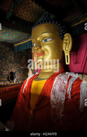 Uomo che ammira la statua in rame e oro dorato del Buddha Gautama a Shey Gompa nel monastero di Thiksay, Ladakh, India, patrimonio culturale, arte spirituale Foto Stock