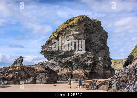 Una delle icone rock pile a Bedruthan Steps torreggia su due turisti. La Cornovaglia. Foto Stock