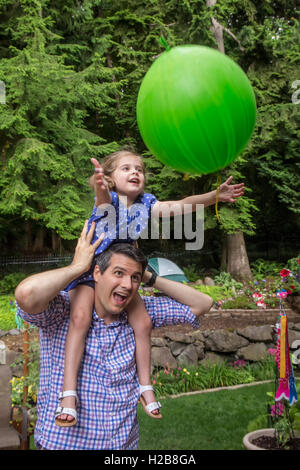 Trentaquattro anni di padre tenendo la sua figlia di tre anni come lei le catture di un palloncino si lancia al suo Foto Stock