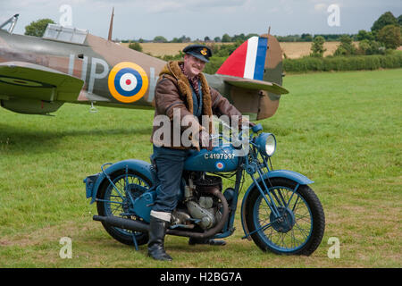 Re-Enactor vestita come una battaglia di Bretagna poste pilota con un Hawker Hurricane fighter e un periodo di RAF autentico ciclo motore Foto Stock