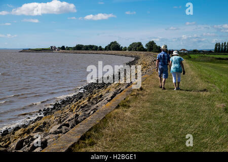 Walkers sul sentiero costiero e parete del mare, Goldcliff vicino a Newport, Monmouthshire, Wales, Regno Unito, Severn Estuary Foto Stock