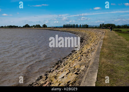 Walker sul sentiero costiero e parete del mare, Goldcliff vicino a Newport, Monmouthshire, Wales, Regno Unito, Severn Estuary Foto Stock