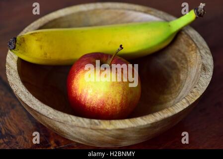 Coppa di frutta sul tavolo da cucina contenenti una mela rossa e una banana. Foto Stock