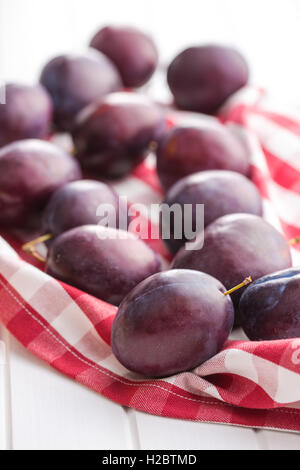 Fresche susine mature sul tovagliolo a scacchi. Foto Stock