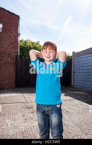 Un giovane ragazzo in piedi fuori in una giornata di sole indossando un blu brillante Beaver Scout maglietta uniforme Foto Stock
