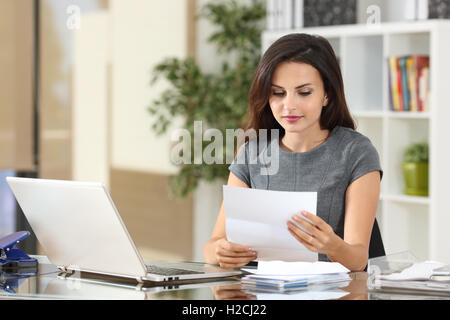 Ritratto di una imprenditrice lavorando in ufficio la lettura di una lettera di un desktop Foto Stock