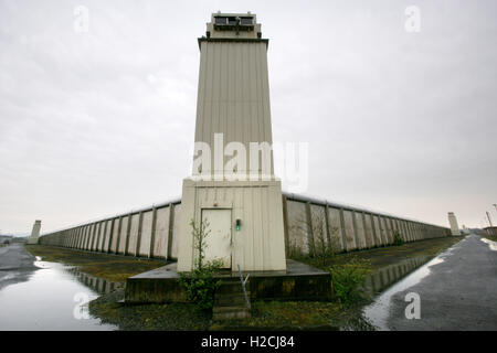 Una torre di avvistamento e parete perimetrale segna il confine dell'ex carcere di Maze, a ovest di Belfast in Irlanda del Nord, Regno Unito Foto Stock