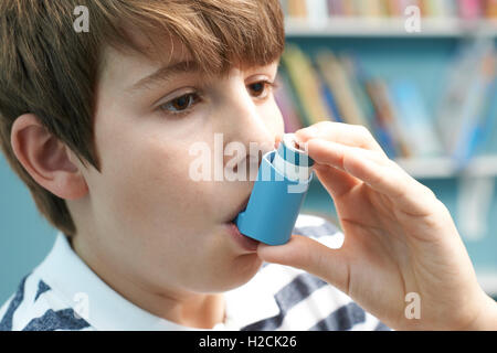 Boy utilizzando Inalatore per trattare asma attacco Foto Stock