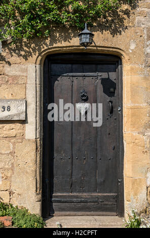 Porta di Cotswold cottage in pietra con la vecchia porta di legno Foto Stock