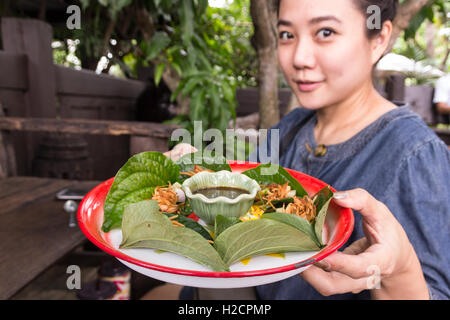 Donna tenere Miang Kum (Leaf-Wrapped Bite-Size antipasto) cibo tailandese vassoio Foto Stock