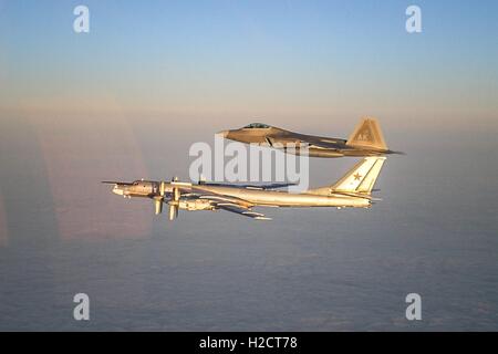 Un U.S. Air Force F Raptor stealth Tactical Fighter Aircraft accompagnatrici un russo TU-95 Orso bombardiere strategico in volo Novembre 22, 2007 vicino all'Alaskan NORAD regione dello spazio aereo. Foto Stock