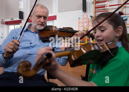 Leader laburista Jeremy Corbyn è dato una lezione di violino da dieci anni di Jessica Kelly durante una visita alla fede la scuola primaria a Liverpool, dove ha incontrato i bambini che partecipano nel progetto di armonia, il quale è supportato dalla Royal Liverpool Philharmonic Orchestra e sta aiutando a scuola i bambini imparano a suonare strumenti musicali. Foto Stock