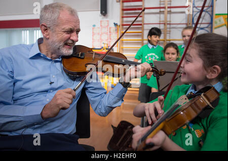 Leader laburista Jeremy Corbyn è dato una lezione di violino da dieci anni di Jessica Kelly durante una visita alla fede la scuola primaria a Liverpool, dove ha incontrato i bambini che partecipano nel progetto di armonia, il quale è supportato dalla Royal Liverpool Philharmonic Orchestra e sta aiutando a scuola i bambini imparano a suonare strumenti musicali. Foto Stock