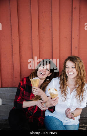 Due donne seduta su una panchina a mangiare il gelato. Foto Stock