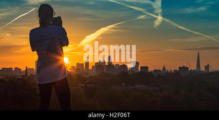 Primrose Hill, Londra, 28 ottobre 2016. Regno Unito Meteo: una donna fotografie lo skyline della città come alba rompe su Londra. Credito: Paolo Davey/Alamy Live News Foto Stock