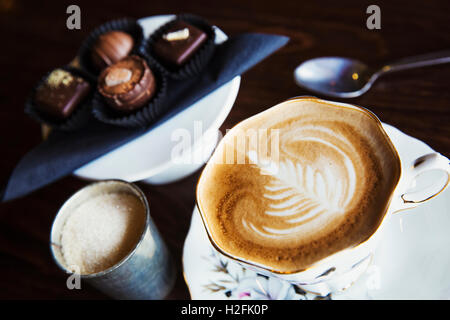 Mano assortiti cioccolatini fatti su una piastra. Una tazza di caffè. Foto Stock