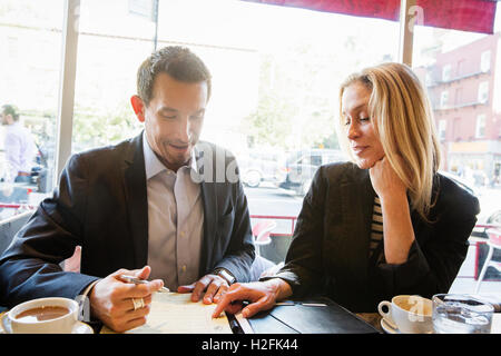 Imprenditrice e imprenditore seduti ad un tavolo in un caffè, un pranzo di lavoro, un incontro. Foto Stock