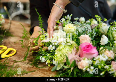 Una donna che lavora su una disposizione del fiore, un fiorista qualificato. Foto Stock