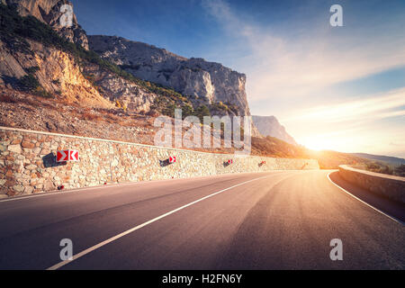 Strada asfaltata. Paesaggio colorato con una bella strada di montagna con un asfalto perfetto e la segnaletica stradale. Sunrise in estate. Vintage Foto Stock