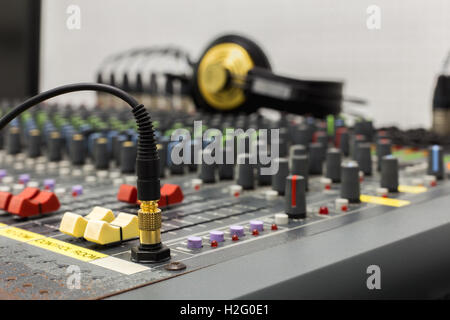 Fotografia di un DJ il jack per le cuffie nella presa, preso da vicino con una profondità di campo ridotta. Fader di sfondo e le cuffie. Foto Stock