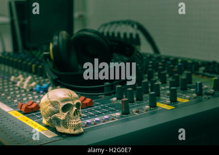 Cranio umano in appoggio su di un mixer audio. Sullo sfondo delle console mixer e cuffie,TONO Vintage Foto Stock