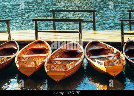 Piccole barche di legno inserito e vincolato al molo di vuoto sul lago Foto Stock