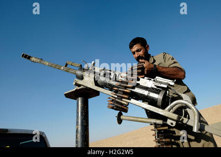 Un combattente curdo del popolo della Forze di Difesa HPG l ala militare del Partito dei Lavoratori del Kurdistan PKK proiettili di caricamento in una pesante DShK mitragliatrice montata su un open-backed civile carrello elevatore di prelievo Foto Stock