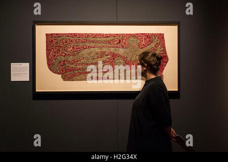 Una donna che guarda la parte del cavallo di un cacciatore di animali da pelliccia sul display come parte dell'Opus Anglicanum: Capolavori di Inglese Medievale mostra di ricamo presso il Victoria and Albert Museum (V&A) a Londra. Foto Stock