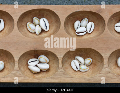 Dettaglio di un mancala board con conchiglie. Mancala è un tradizionale gioco da tavolo giocato in tutto il mondo. Foto Stock