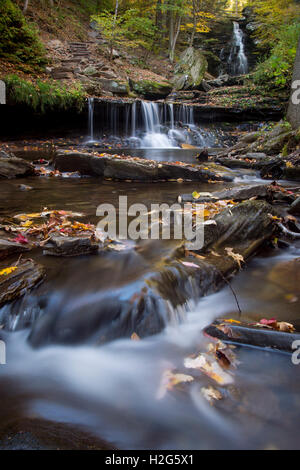 Una piccola cascata circondata da sgargianti colori autunnali. Foto Stock