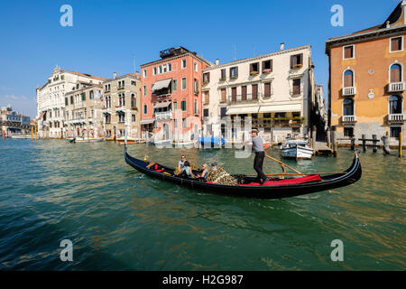 Gondola sul Canal Grande con passeggeri per turismo a Venezia, Italia Avvicinamento ponte sul Canal Grande. Tarda estate, cielo blu Foto Stock