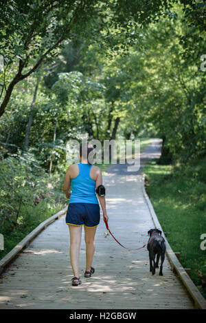 Donna, indossando il tracker di fitness e il cane a camminare su un sentiero Foto Stock