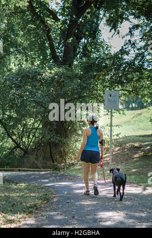 Una donna che indossa il tracker di fitness e il suo cane a camminare su un sentiero pubblico Foto Stock