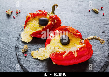 Rosso Farcite i peperoni con il formaggio feta e olive nere su sfondo di pietra. Foto Stock